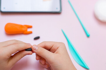 A child sculpts plasticine figures from a smartphone. Copy space. Selective focus.