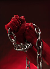 bloodied hands clenched into fists in the shackles of a metal chain symbolize slavery, protest and...