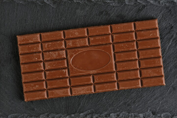 Bar milk chocolate on a black slate.