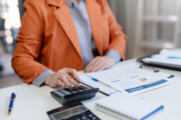 Close-up of businesswoman hands using a calculator to check company finances and earnings and budget. Business woman calculating monthly expenses, managing budget,  papers, loan documents, invoices.