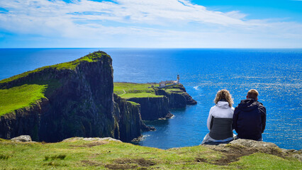 Couple watching Neist Point and Lighthouse landscape, Isle of Skye, Scotland landmark