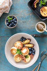 Cottage cheese pancakes, cheesecakes, ricotta fritters with fresh blueberries, currants and peaches on a plate. Healthy and delicious breakfast for the holiday. Blue wooden background