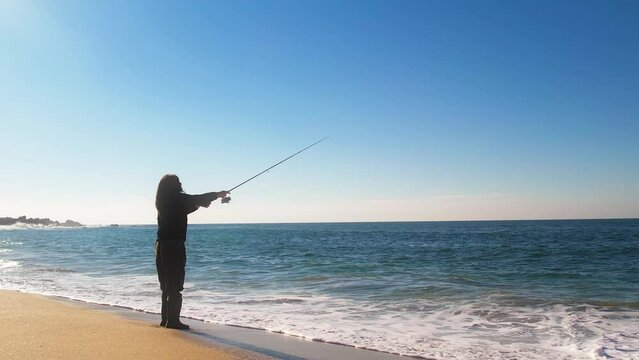 Woman fishing on the shoreline on a beautiful and peaceful beach