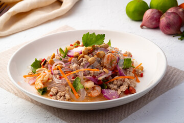 Spicy Glass Seaweed noodle Salad with Minced Pork (yum sen kaew) is a type of Thai salad made with clear Kelp noodle and meat in white plate © Kritchai