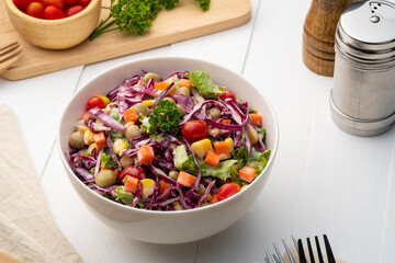 Fresh homemade mix fruit and vegetable salad on white bowl,creamy salad with carrot, Purple cabbage, tomato, corn, green peas and mayonnaise dressing