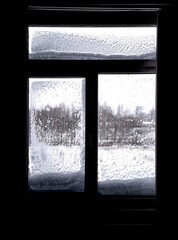 Window in winter with snow and ice on the glass. The silhouette is against the light