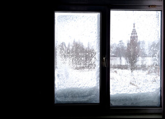 Fototapeta na wymiar Window in winter with snow and ice on the glass. The silhouette is against the light
