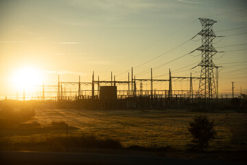 image of a high voltage power plant in silhouette at sunrise.