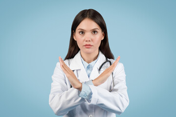 Doctor in coat gives stop sign, blue background