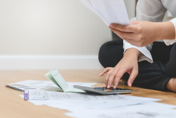 Couple sitting on the floor calculating loan debt and household expense with calculator