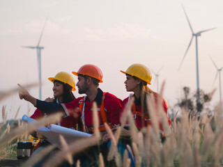 Fototapeta premium Group of maintenance engineers preparing and planning inspection of wind turbines, holding tablets, looking at wind turbines