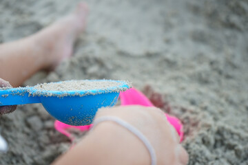 Top view of the sand in the container with hands of child play with the toy