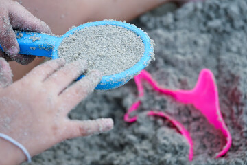 Top view of the sand beach with hands of child play with the toy