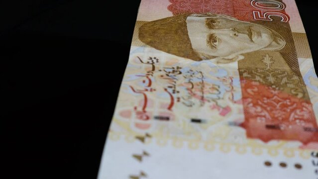 A closeup of Pak Rupee banknotes of 5000 denominations cash stack with reflection on the rotating glass table