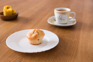 Fresh muffin with coffee for breakfast. Candel on the desk.