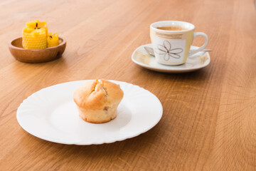 Fresh muffin with coffee for breakfast. Candel on the desk.