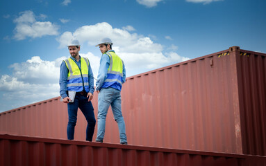 Engineer team wears PPE checking container storage with cargo container background at sunset....