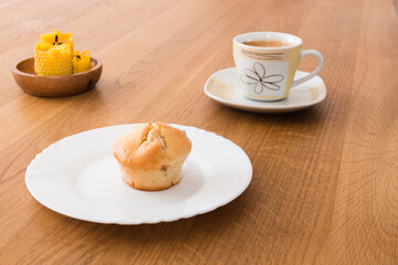 Fresh muffin with coffee for breakfast. Candel on the desk.
