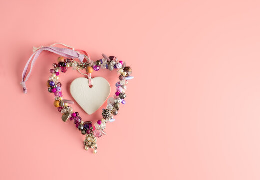 Valentines day wedding concept  romance Garland heart of pearls and precious gems framing a white heart  isolated on a pink  background