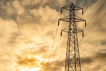 Dramatic evening view of an electricity pylon with the cables being fed by a nearby Nuclear Power station in the UK.
