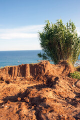 Fototapeta na wymiar Small hill with reddish soil mixed with sand facing the sea near the harbor.