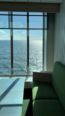 green sofa against the background of panoramic windows in sunny weather. Interior design
