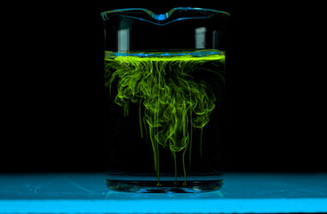 Dissolution and spread of a yellow substance in a flask with a clear liquid.