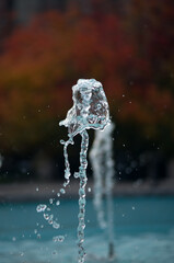 The stream of the fountain froze against the backdrop of the autumn park - 709256619