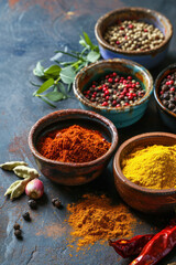 Different spices in a small bowls on stone background.