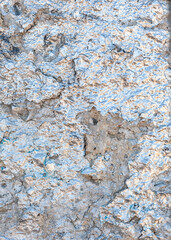 The crumbling plaster wall is painted with silver glitter paint have a bluish and yellowish tint