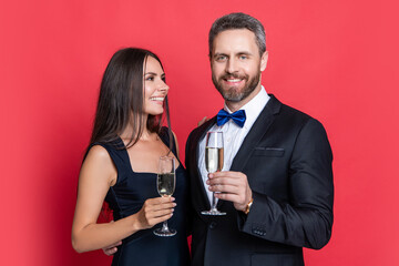 Celebrate anniversary. Couple in love celebrate engagement. Elegant couple drink champagne isolated on red. Couple at formal occasion. Romantic date celebrations. Valentines day. Merry couple