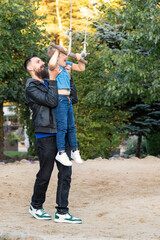 Father and son playing on outdoor swing park. Happy family, closeness of father and son.