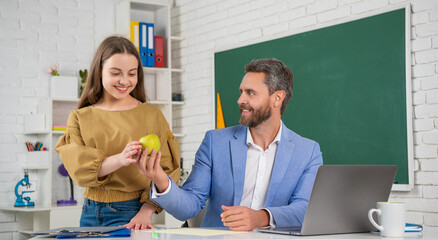 smiling teen child with man teacher in classroom. education