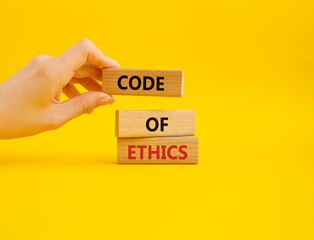 Code of ethics symbol. Concept words Code of ethics on wooden blocks. Beautiful yellow background....