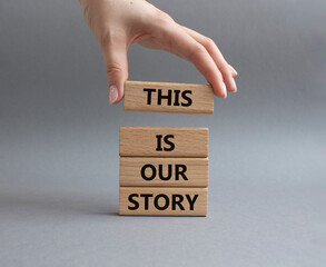 This is our Story symbol. Wooden blocks with words This is our Story. Businessman hand. Beautiful grey background. Business and This is our Story concept. Copy space.