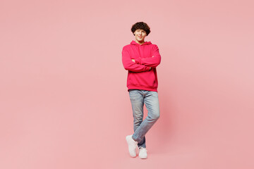 Full body fun smiling happy young Caucasian man he wears hoody casual clothes hold hands crossed folded look camera isolated on plain pastel light pink background studio portrait. Lifestyle concept.