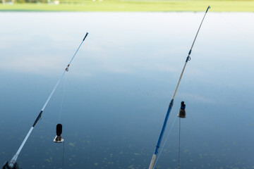 Fishing rod with a stretched fishing line and bells on the background of the water. Background on the theme of recreation on fishing.