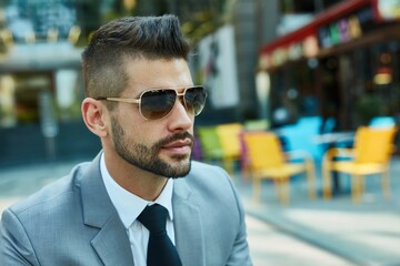 Portrait of confident businessman outdoor wearing suit and sunglasses.