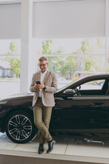 Full body adult rich man customer male buyer client wear grey suit use mobile cell phone choose...