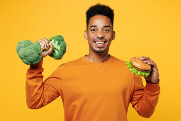 Young man wear orange sweatshirt casual clothes hold broccoli pov dumbbell burger choose what to...