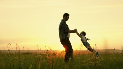 Happy family, dad plays with child as pilot, circling child by hands, kid rejoices and laughs....