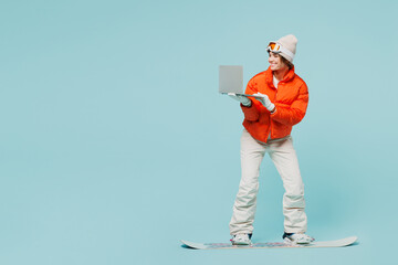 Full body young IT woman wear padded windbreaker jacket hat ski goggles mask snowboarding use...