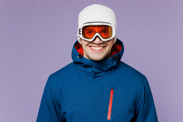 Skier cheerful smiling satisfied happy man he wear warm blue windbreaker jacket ski goggles mask hat look camera spend extreme weekend winter season in mountains isolated on plain purple background.