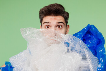 Close up young shocked sad man he wear blue t-shirt white title volunteer hold pile of polyethylene...