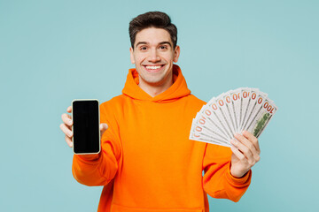 Young man wear orange hoody casual clothes hold in hand fan of cash money in dollar banknotes use...