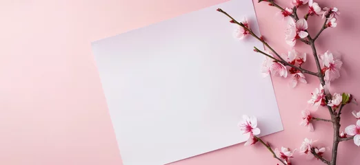 Tuinposter Delicate cherry blossoms branch over a blank white canvas, poised against a soft pink background, perfect for spring messages and thoughtful notes. © Mirador