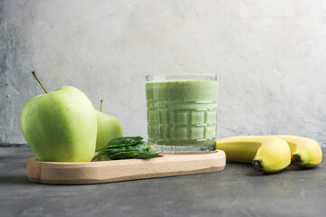 Green detox smoothie in a glass, blended vegetarian drink from spinach leaves, apple and banana...