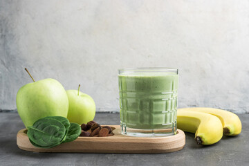 Green detox smoothie in a glass, blended vegetarian drink from spinach leaves, apple, banana fruit...