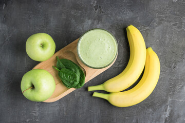 Green detox smoothie in a glass, blended vegetarian drink from spinach leaves, apple and banana...