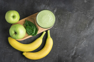 Green detox smoothie in a glass, blended vegetarian drink from spinach leaves, apple and banana...